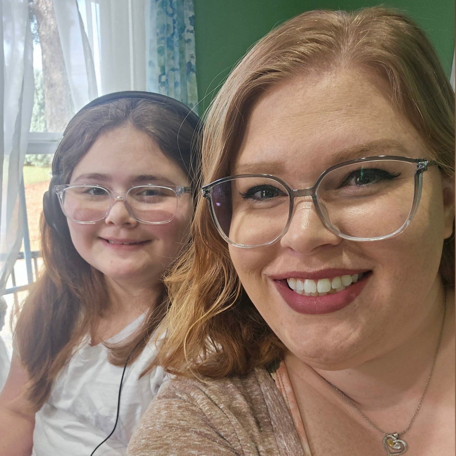 Two women wearing glasses smiling at the camera indoors.